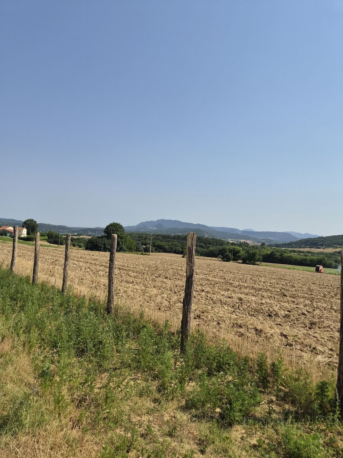 Champ labouré avec clôture en bois, montagnes en arrière-plan